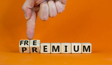 Premium ya da Freemium sembolü. İşadamı ahşap küpleri dönüştürür ve 'premium' kelimesini 'freemium' a çevirir. Güzel turuncu arka plan. İş, prim ya da özgürlük konsepti. Boşluğu kopyala.