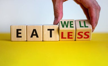 Eat well or eat less symbol. Businessman turns cubes and changes words 'eat less' to 'eat well'. Beautiful white and yellow background. Business, eat well or less concept. Copy space.