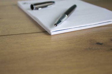 Beautiful metalic pen and cap on wooden table. White note. Beautiful wooden background. Business, office concept. Copy space.