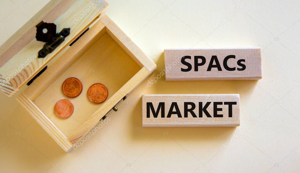 SPACs market symbol. Wooden blocks with words 'SPACs, special purpose acquisition companies market' on beautiful white background, copy space. Chest with coins. Business and SPACs market concept.