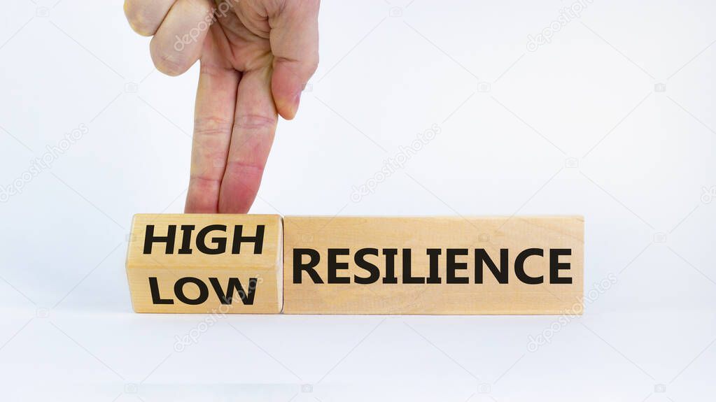 High or low resilience symbol. Businessman flips wooden cubes and changes words 'low resilience' to 'high resilience'. Beautiful white background, copy space. Business, high resilience concept.