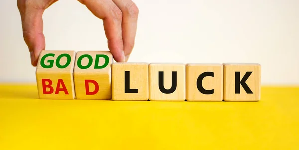 Good or bad luck symbol. Businessman turns wooden cubes and changes words 'bad luck' to 'good luck'. Beautiful yellow table, white background, copy space. Business and good or bad luck concept.