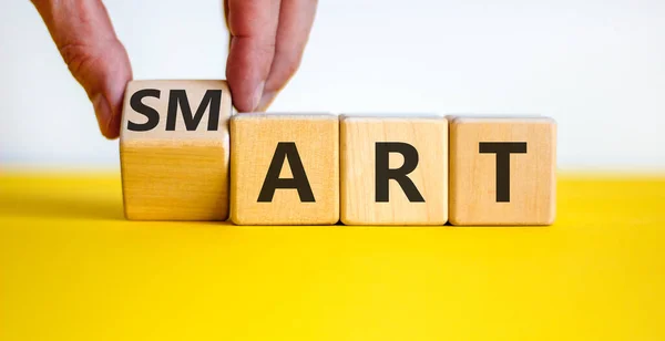Smart art symbol. Businessman turns the cube and changes the word \'smart\' to \'art\'. Beautiful yellow table, white background. Business and smart art concept, copy space.