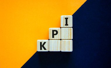KPI, key performance indicator symbol. Wood cubes with words 'KPI, key performance indicator' on orange background, copy space. Businessman hand. Business and KPI, key performance indicator concept.
