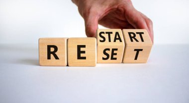 Reset and restart symbol. Businessman hand turns cubes and changes the word 'reset' to 'restart'. Beautiful white background. Business and reset - restart concept. Copy space.