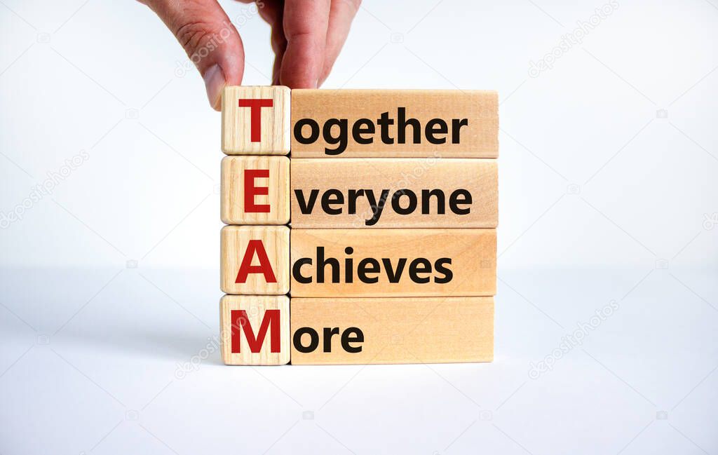 TEAM, together everyone achieves more symbol. Wooden cubes with words 'TEAM, together everyone achieves more'. Beautiful white background, copy space. Business, motivational and TEAM concept.