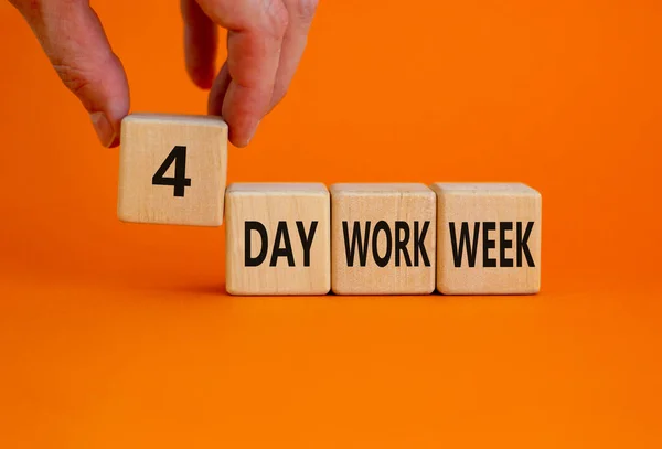 4 day work week symbol. Businessman holds the cube with words \'4 day work week\'. Beautiful orange background. Copy space. Business and 4 or 5 day work week concept.