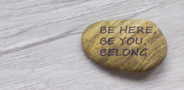 Be here, be you, belong symbol. Beautiful stone with words 'Be here, be you, belong' on beautiful white wooden background. Diversity, business, inclusion and belonging concept. clipart