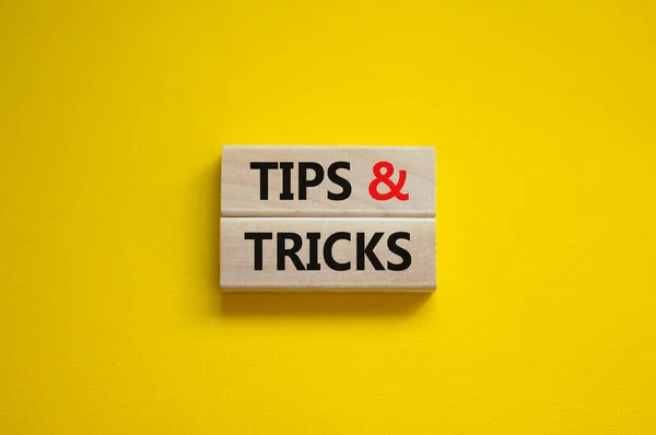 Tips and tricks symbol. Wooden blocks with words \'Tips and tricks\'. Beautiful yellow background. Business, tips and tricks concept. Copy space.