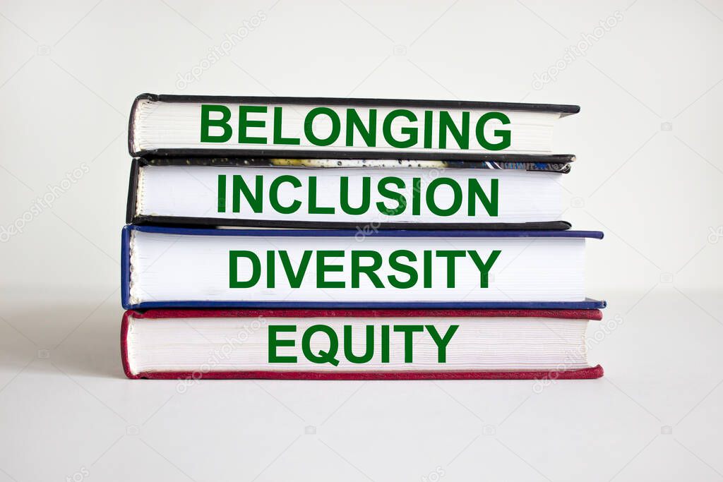 Belonging symbol. Books with words 'belonging, inclusion, diversity equity' on beautiful white table, white background. Business, belonging, diversity and inclusion concept. Copy space.