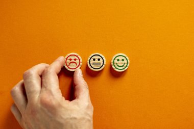 Kalite ve geri bildirim sembolü. Tahta çemberlerden yapılmış çeşitli emoticonlar. Güzel turuncu arka plan. Kalite ve geri bildirim kavramsal görüntüsü. Müşteri eli. İş ve geri bildirim kavramı.