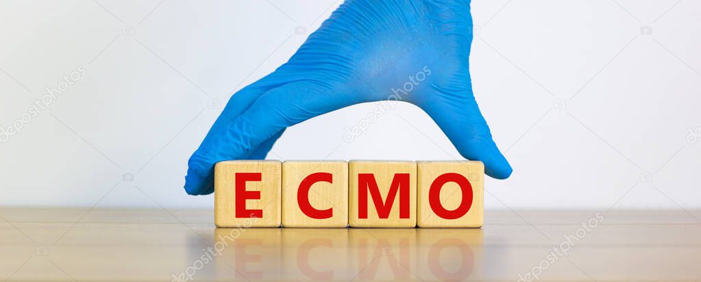 ECMO symbol. Concept words 'ECMO, Extra Corporeal Membrane Oxygenation' on cubes on a beautiful white background. Doctor hand in blue glove. Copy space. Medical, ECMO concept.