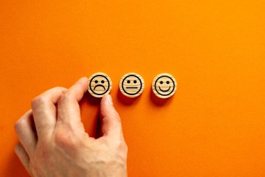 Kalite ve geri bildirim sembolü. Tahta çemberlerden yapılmış çeşitli emoticonlar. Güzel turuncu arka plan. Kalite ve geri bildirim kavramsal görüntüsü. Müşteri eli. İş ve geri bildirim kavramı.
