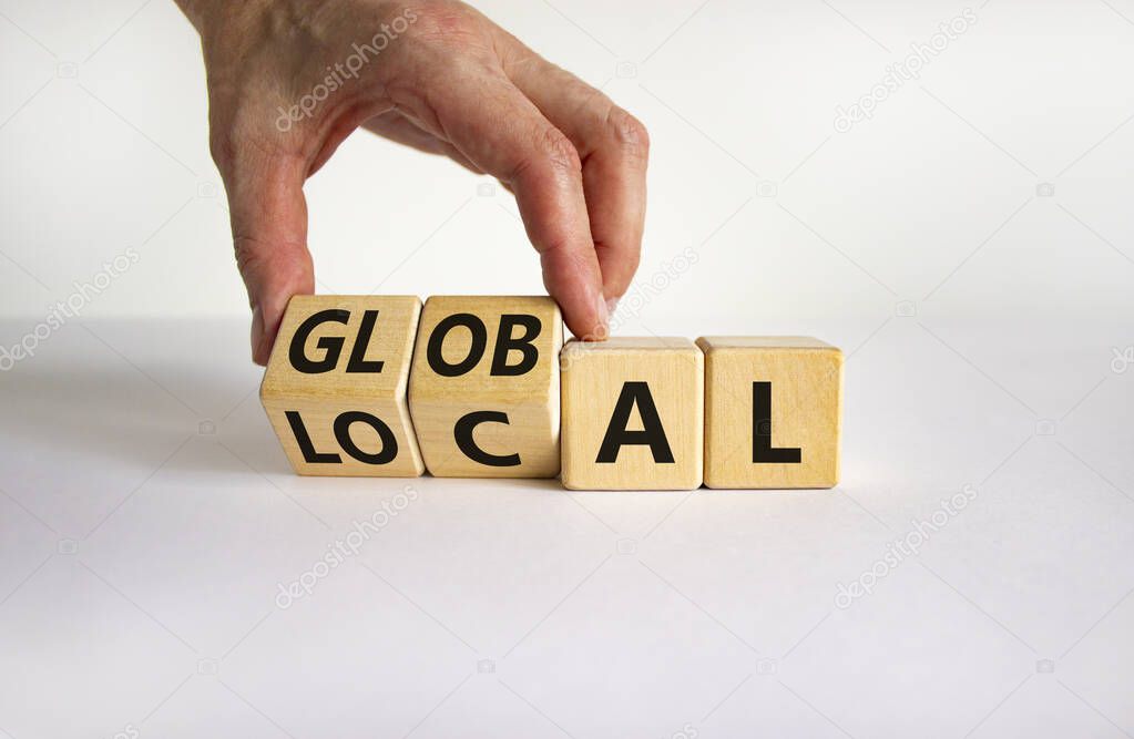 Local or global symbol. Businessman turns wooden cubes and changes the word 'local' to 'global'. Beautiful white table, white background. Business and local or global concept. Copy space.