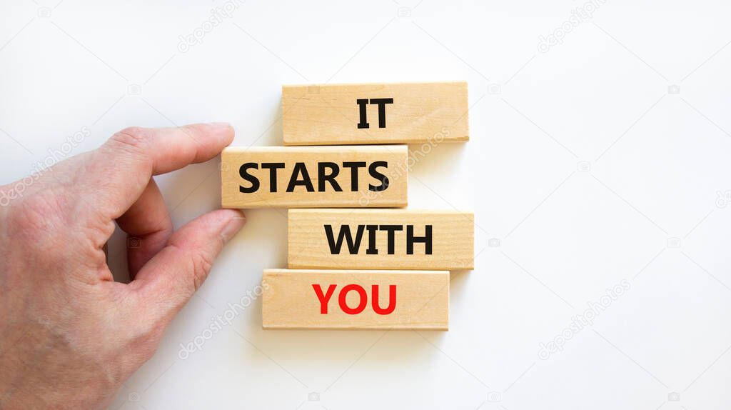 It starts with you symbol. Wooden blocks with words 'it starts with you' on beautiful white background. Businessman hand. Business, motivational and it starts with you concept. Copy space.