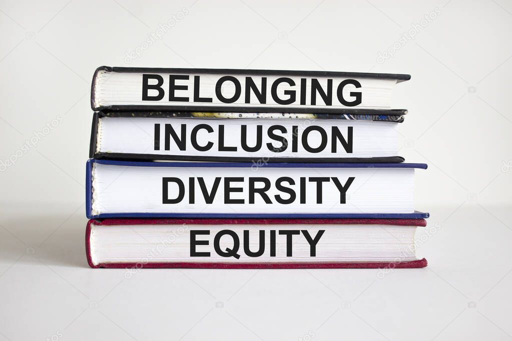 Belonging symbol. Books with words 'belonging, inclusion, diversity equity' on beautiful white table, white background. Business, belonging, diversity and inclusion concept. Copy space.