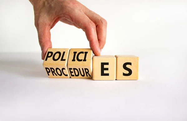 Policies vs procedures symbol. Businessman turns wooden cubes, changes the word \'procedures\' to \'policies\'. Beautiful white table, white background, copy space. Business, policies, procedures concept.