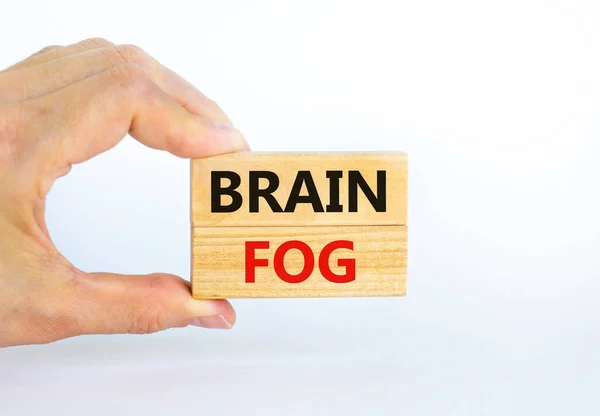 Medical and COVID-19 Pandemic Coronavirus brain fog symbol. Doctor holds wooden blocks with words \'brain fog\'. Beautiful white background. Copy space. Medical and covid-19 brain fog concept.