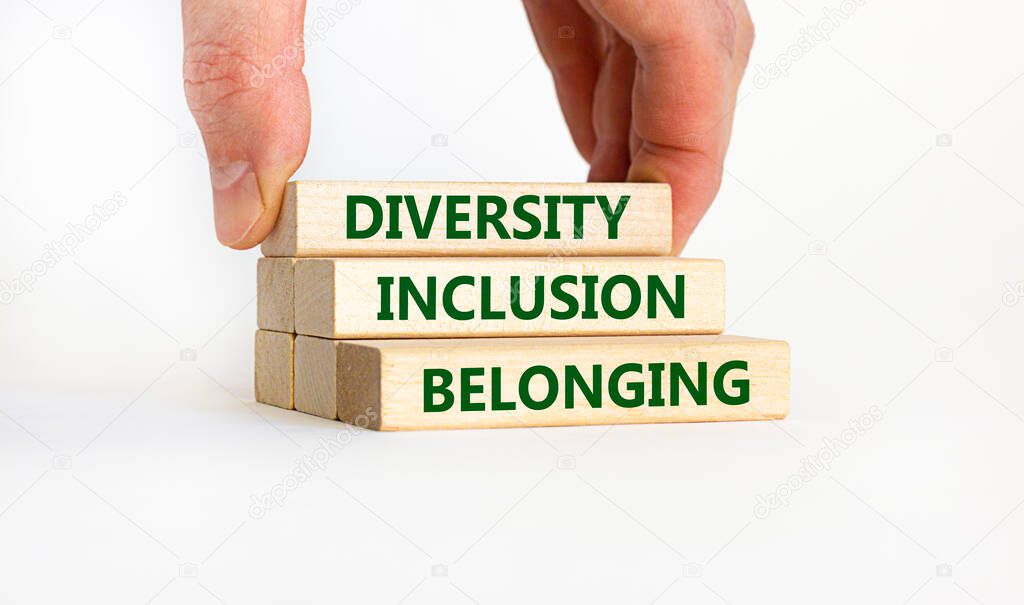 Diversity, inclusion and belonging symbol. Wooden blocks with words 'diversity, inclusion, belonging' on beautiful white background. Male hand. Diversity, business, inclusion and belonging concept.