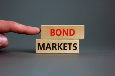 Tahvil piyasası sembolü. Gri arka planda 'Bond piyasaları' yazan tahta bloklar, kopyalama alanı. İşadamı eli. İş ve tahvil piyasaları kavramı.