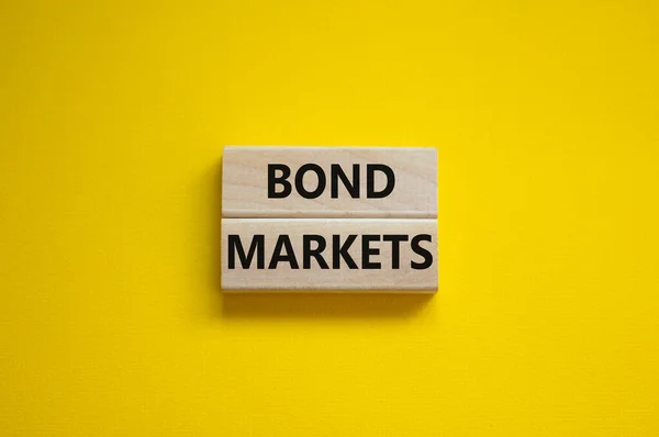 Bond markets symbol. Wooden blocks with words \'Bond markets\' on beautiful yellow background, copy space. Business and bond markets concept.