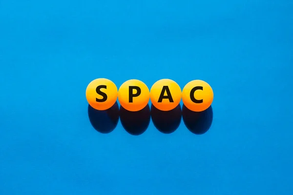 SPAC, special purpose acquisition company symbol. Orange table tennis balls with the word \'SPAC, special purpose acquisition company\'. Beautiful blue background, copy space. Medical, SPAC concept.