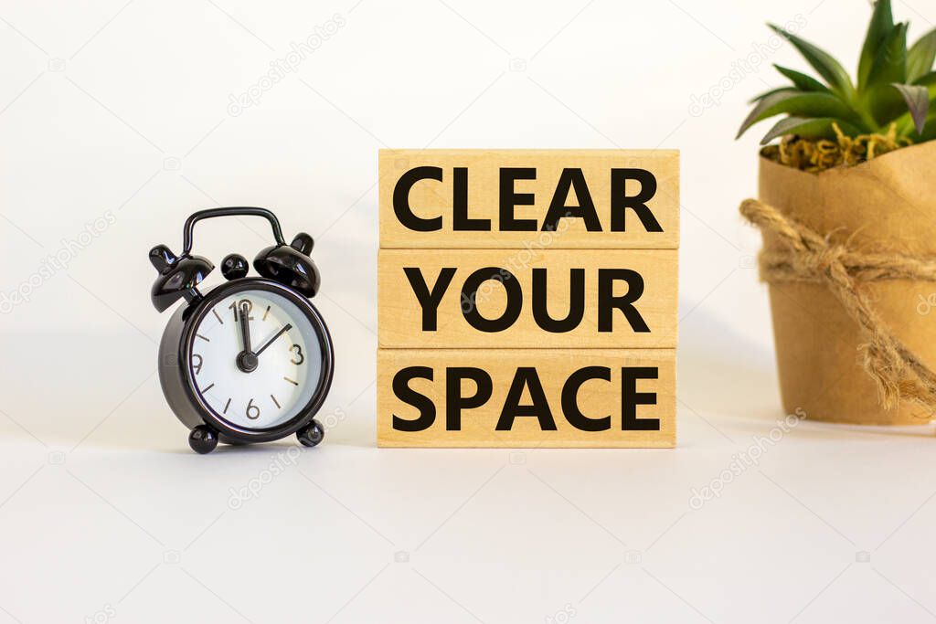 Clear your space symbol. Wooden blocks with words 'Clear your space'. Beautiful white background, black alarm clock, house plant. Business, clear your space concept, copy space.