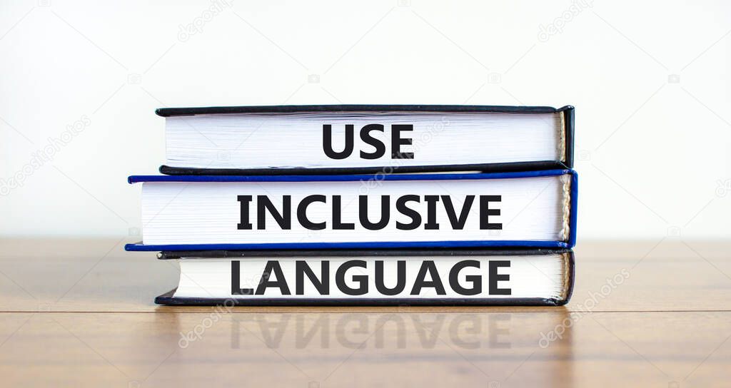 Use inclusive language symbol. Books with words 'Use inclusive language' on beautiful wooden table, white background. Business and use inclusive language concept. Copy space.