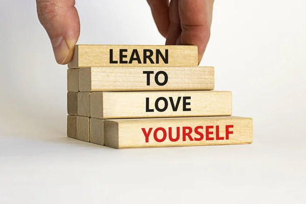 Learn to love yourself symbol. Wooden blocks with words \'Learn to love yourself \' on beautiful white background. Businessman hand. Business, motivational and love yourself concept. Copy space.