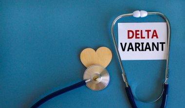 Yeni Covid-19 delta varyant sembolü. Beyaz kart, 'delta versiyonu' ve steteskop, mavi arka plan. Tahta kalp. Tıbbi ve covid-19 delta değişkeni türü konsepti, boşluğu kopyala.