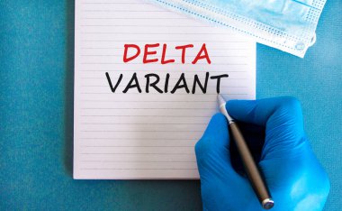 Covid-19 delta varyant sembolü. Doktor mavi eldivenli, kalemli, beyaz kartlı. 'Delta varyantı' kavramını kullan. Tıbbi yüz maskesi. Tıbbi ve COVID-19 delta varyant gerilim konsepti. Boşluğu kopyala.