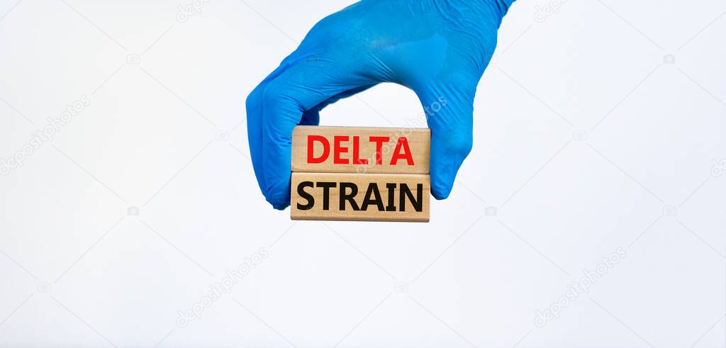 Covid-19 new delta strain symbol. Hand in blue glove holds wooden blocks words 'delta strain'. Beautiful white background. Copy space. Medical and COVID-19 new delta strain variant virus concept.