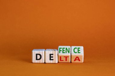 Covid-19 delta varyantı savunma sembolü. Tahta küpü döndürdü ve delta kelimesini savunmak için değiştirdi. Güzel turuncu arka plan. Covid-19 delta varyantı savunma konsepti. Boşluğu kopyala.