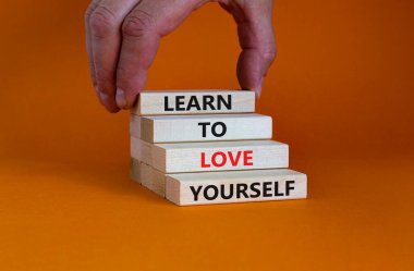 Kendini sevmeyi öğren. Güzel turuncu bir arka planda tahta bloklarda 