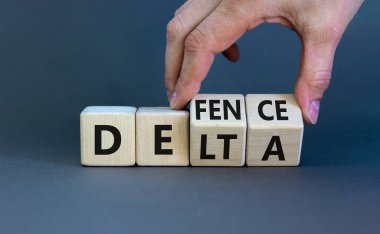 Covid-19 delta varyantı savunma sembolü. Doktor ahşap küpü döndürür ve deltayı savunmaya çevirir. Güzel gri arkaplan. Covid-19 delta varyantı savunma konsepti. Boşluğu kopyala.