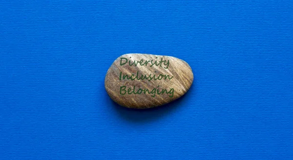 Diversity, inclusion and belonging symbol. Beautiful stone with words diversity inclusion and belonging on beautiful blue background. Diversity, business, inclusion and belonging concept.