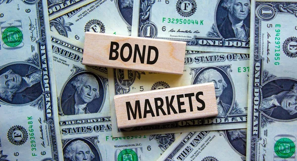 Bond markets symbol. Wooden blocks with words \'Bond markets\' on beautiful background from dollar bills, copy space. Business and bond markets concept.