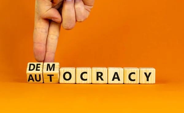 民主主義や自治のシンボル ビジネスマンは木製のキューブを回し 民主主義に単語の自律性を変更します 美しいオレンジの背景 コピースペース ビジネスと民主主義または自治主義の概念 — ストック写真
