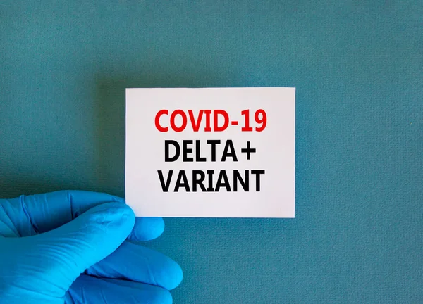stock image Covid-19 delta plus variant strain symbol. Hand in blue glove with white card. Concept words Covid-19 delta plus variant. Medical, COVID-19 delta plus variant strain concept. Copy space.