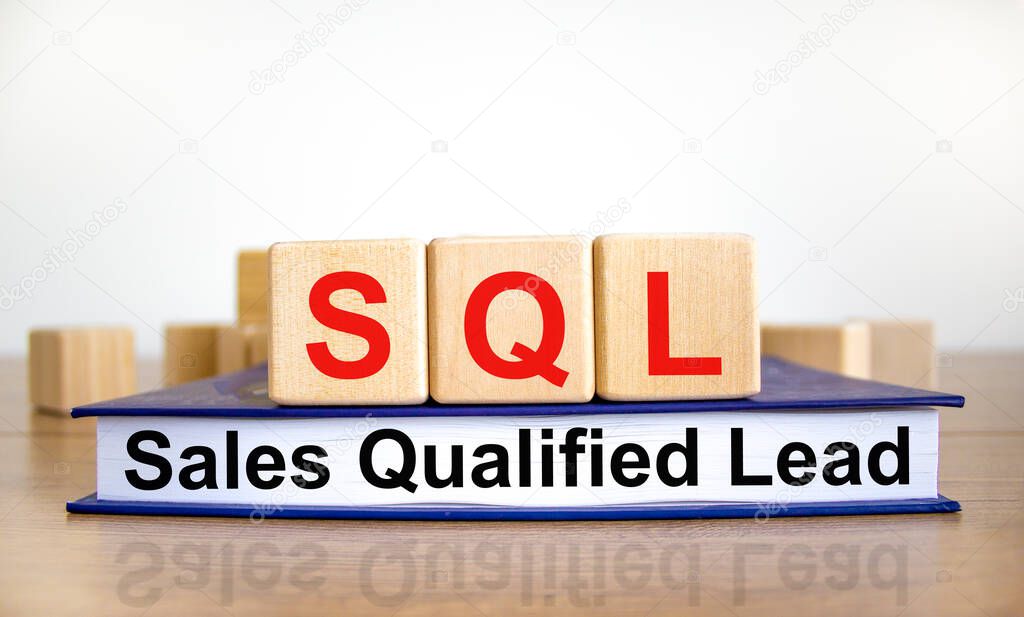 SQL sales qualified lead symbol. Wooden cubes on book with words 'SQL sales qualified lead'. White background. Business and SQL sales qualified lead concept. Copy space.