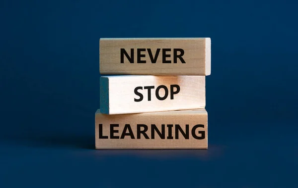 Never stop learning symbol. Wooden blocks with concept words Never stop learning. Beautiful grey background, copy space. Business, educational and never stop learning concept.