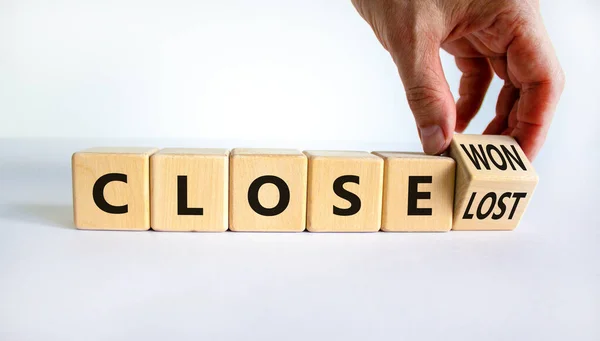 Close won or lost symbol. Businessman turns the wooden cube and changes words Close won to close lost. Beautiful white background, copy space. Business and close won or lost concept.