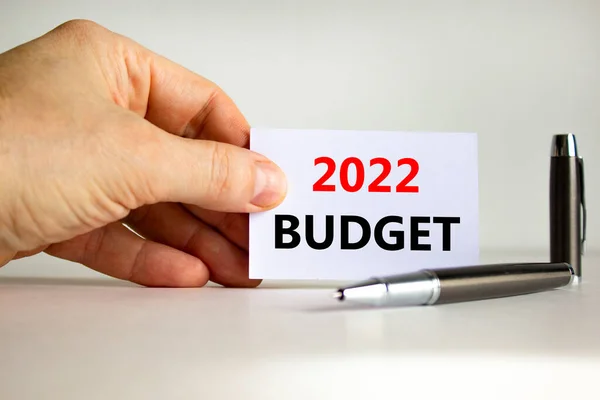 2022 budget new year symbol. White paper with words \'2022 budget\' in businessman hand, metallic pen. Beautiful white background. Business and 2022 budget new year concept. Copy space.