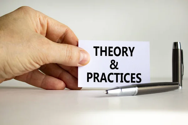 Theory and practice symbol. White paper with words \'Theory and practice\' in businessman hand, metallic pen. Beautiful white background. Business, theory and practice concept. Copy space.