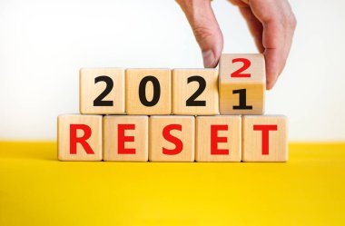 İş planlama konsepti 2022 sıfırlama sembolü. İşadamı ahşap küpü çeviriyor ve '2021' i sıfırla 'yı' 2022 'ye sıfırla' olarak değiştiriyor. Güzel beyaz arka plan, kopyalama alanı. İş ve 2022 konsepti sıfırladı.