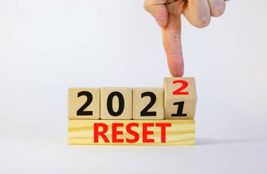 İş planlama konsepti 2022 sıfırlama sembolü. İşadamı ahşap küpü çeviriyor ve '2021' i sıfırla 'yı' 2022 'ye sıfırla' olarak değiştiriyor. Güzel beyaz arka plan, kopyalama alanı. İş ve 2022 konsepti sıfırladı.