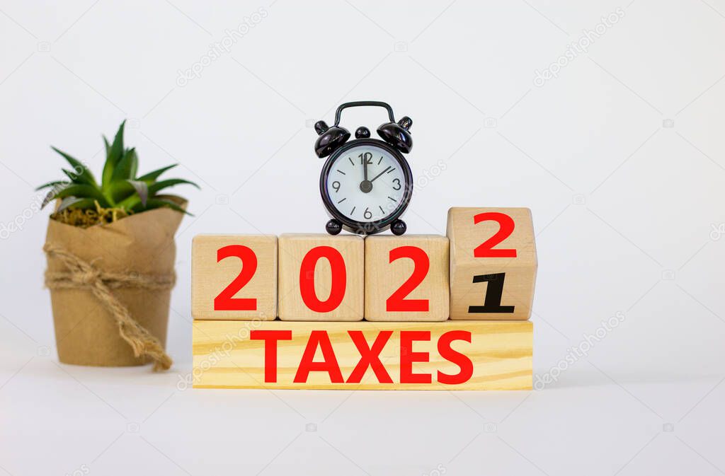 Business concept of taxes planning 2022. Turned a wooden cube and changed words 'Taxes 2021' to 'Taxes 2022'. Beautiful white background, copy space. Business, 2022 taxes concept.