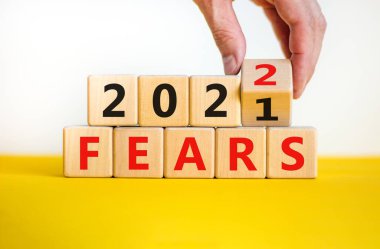 2022 'nin iş planlama kavramı korku sembolü. İş adamı ahşap küpü çevirir ve '2021 Korkusu' nu '2022' ye çevirir. Güzel beyaz arka plan, kopyalama alanı. İş ve korku 2022 konsepti.