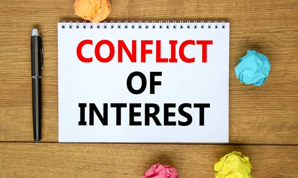 Conflict of interest symbol. Words 'Conflict of interest' on beautiful wooden table, colored paper, black metallic pen. Business, conflict of interest concept, copy space.