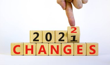 2022 yılının sembolü yeni yılı değiştirir. İşadamı ahşap küpü çeviriyor ve '2021 Değişiklikler 2022' olarak değiştiriyor. Güzel beyaz arka plan, kopyalama alanı. İş dünyası, 2022 kavramı değiştirir.